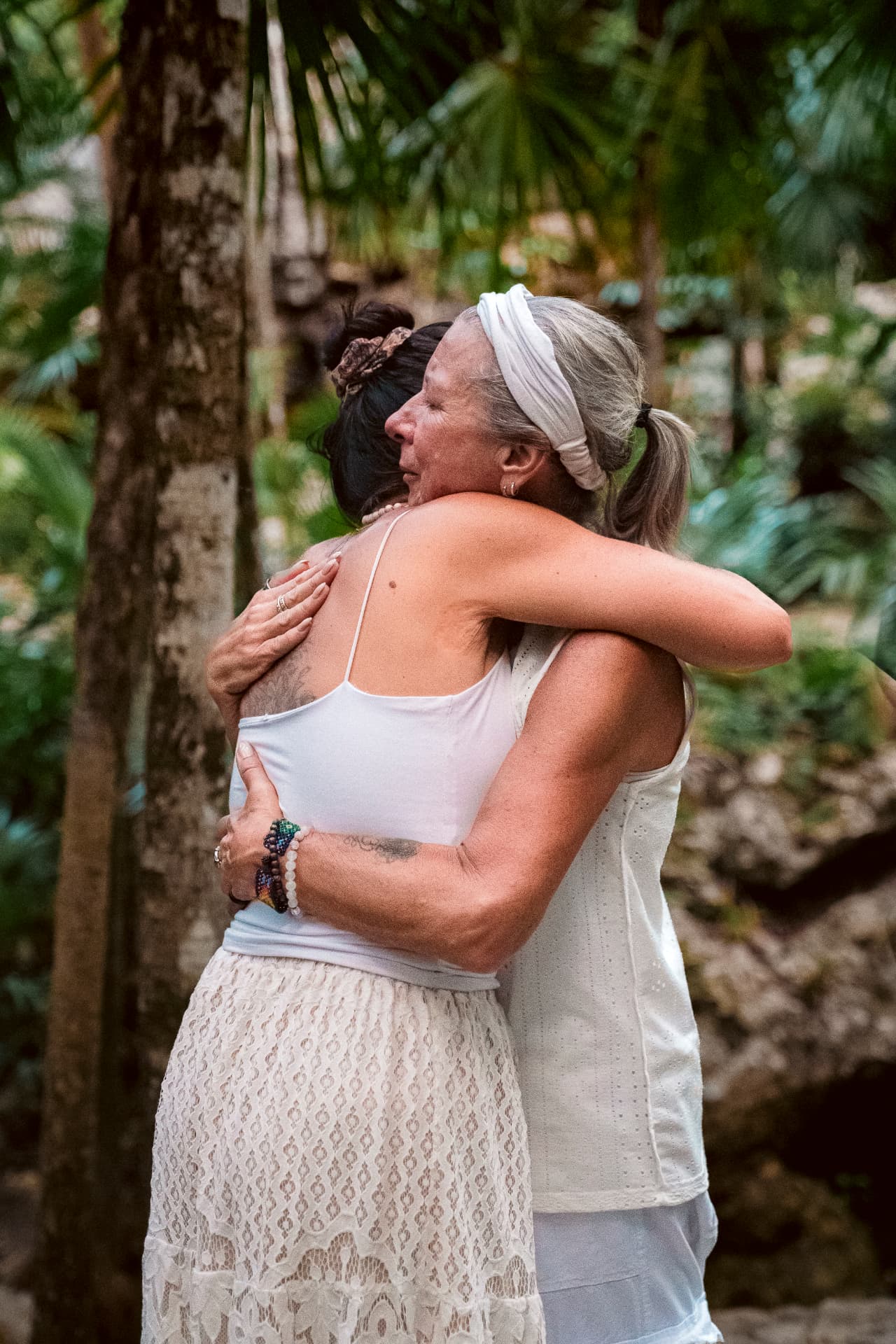 Étreinte émotive entre deux participantes entourées de verdure tropicale