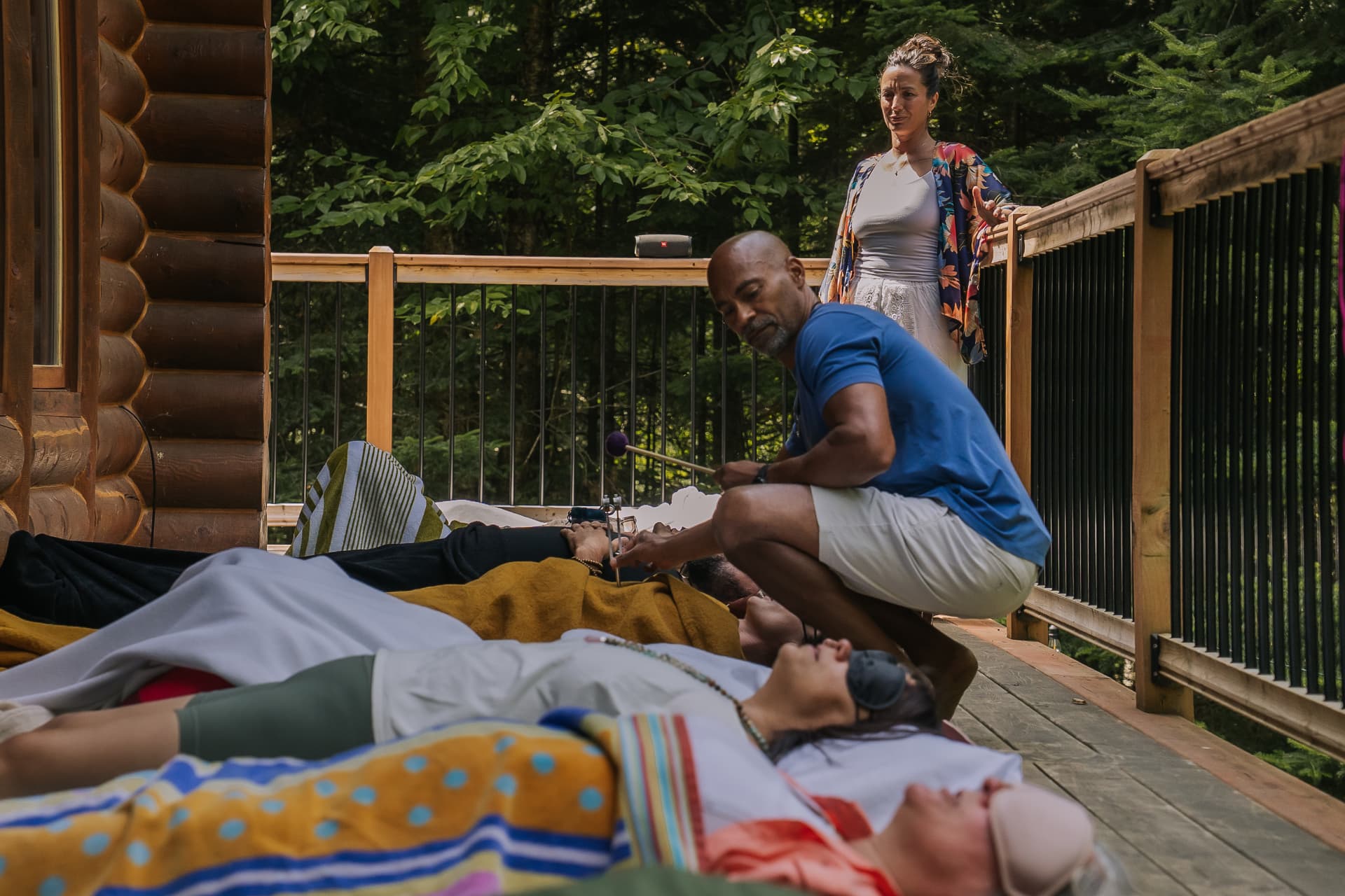 Claude offrant un soin sonore sur la terrasse d'un chalet en forêt