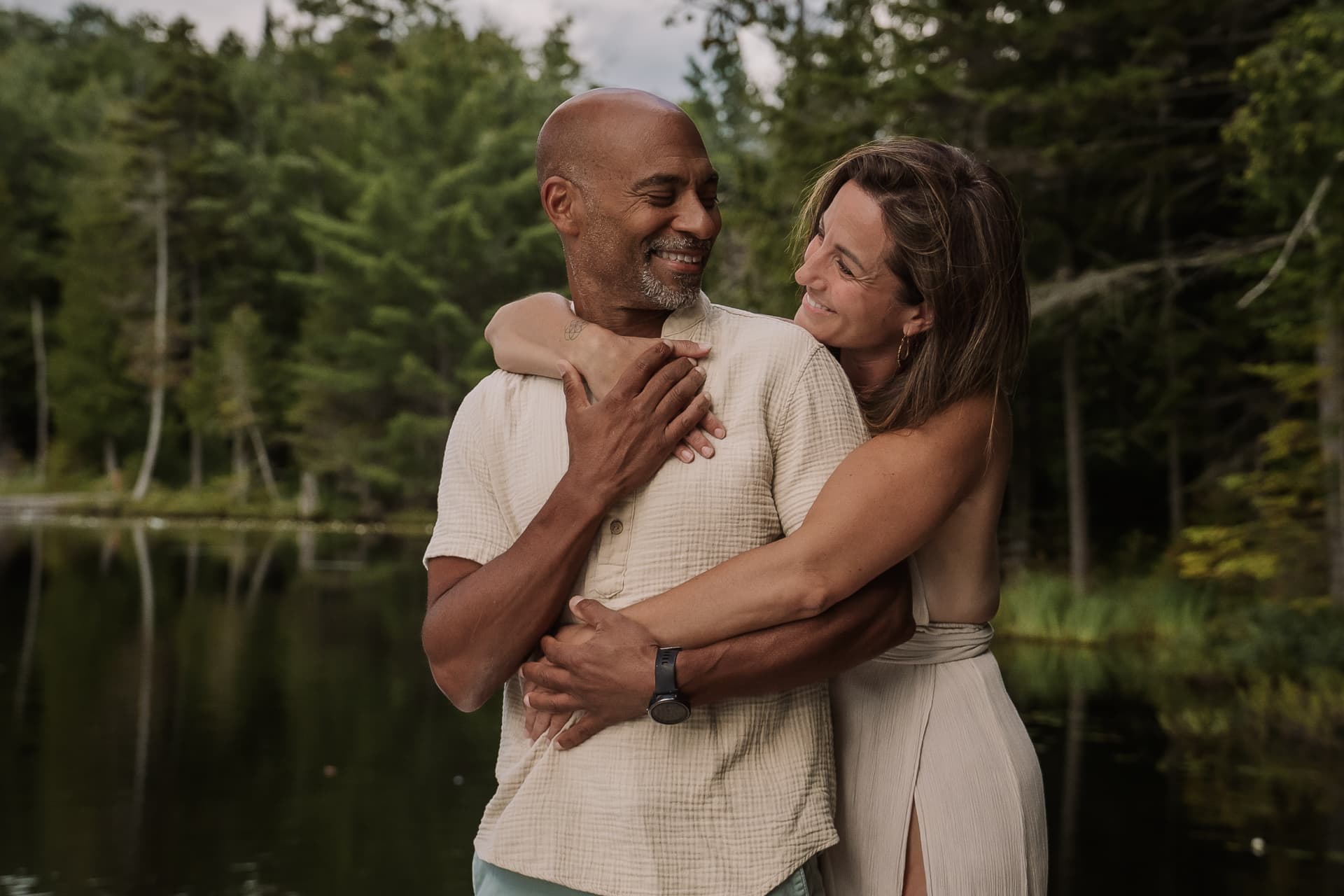 Amélie et Claude enlacés au bord d'un lac en forêt