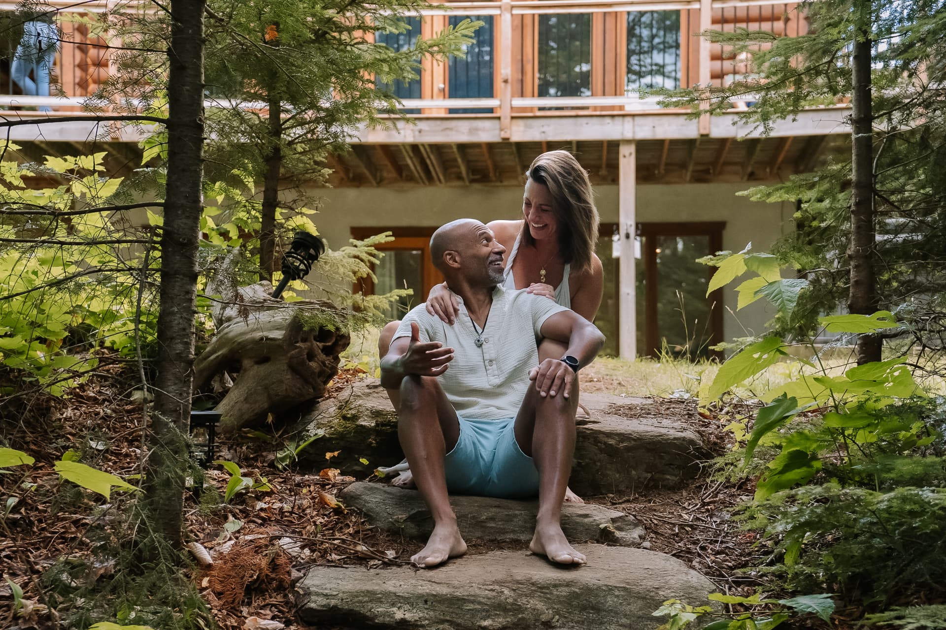 Amélie et Claude riant ensemble, assis sur une pierre en forêt
