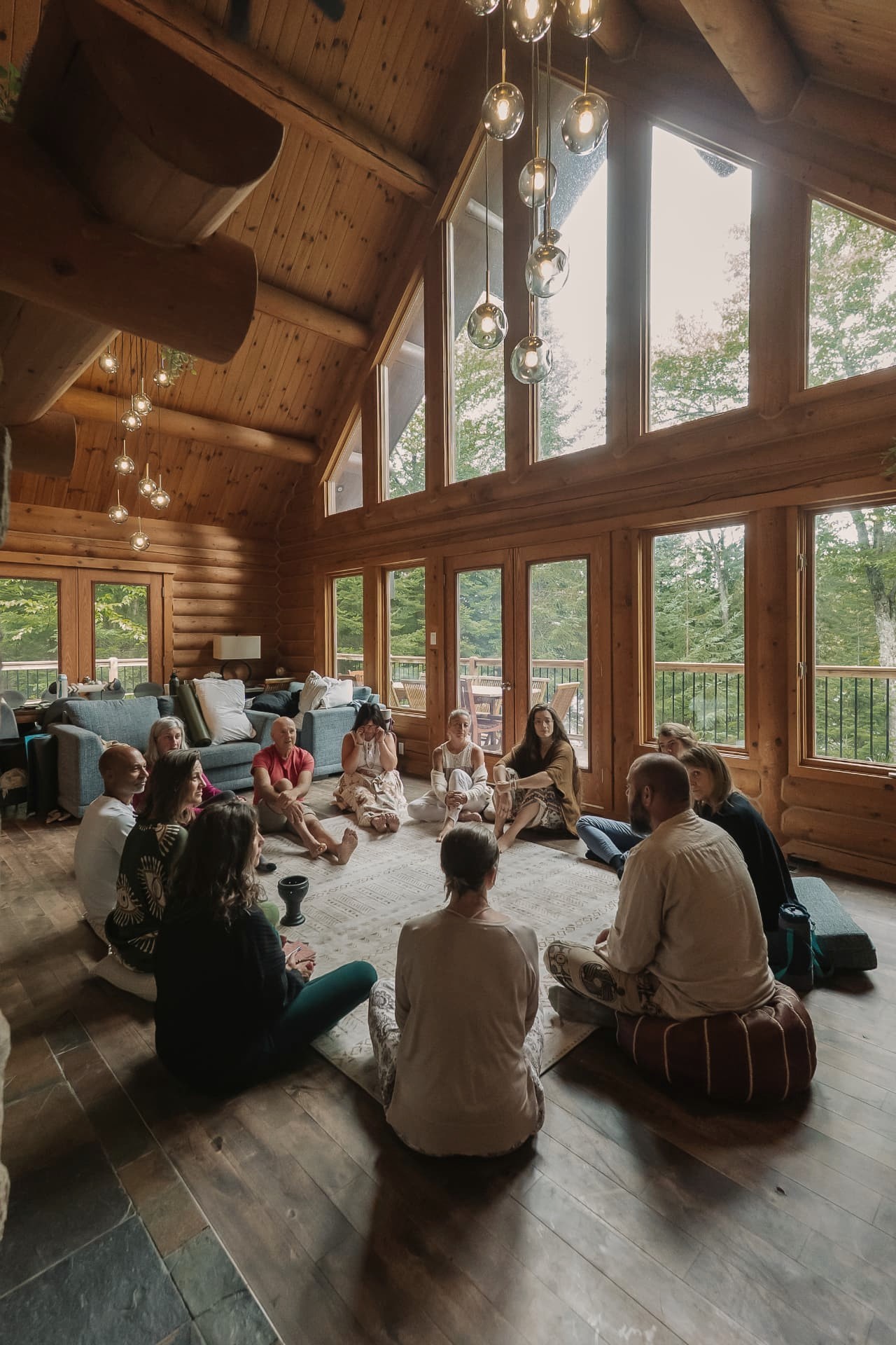 Cercle de participants assis au sol dans un chalet en bois entouré de forêt québécoise