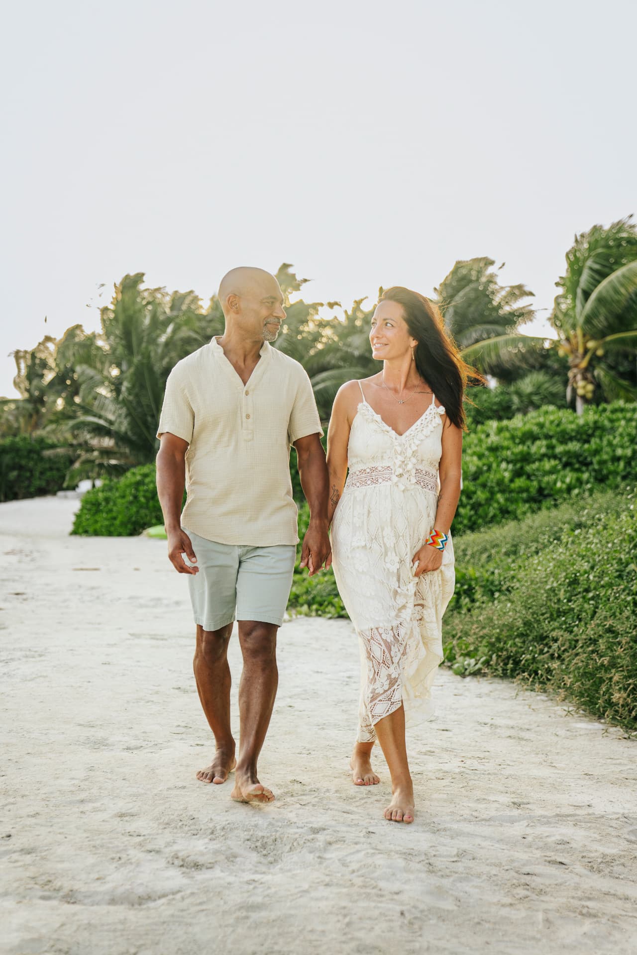 Amélie et Claude marchant pieds nus main dans la main sur un sentier de sable